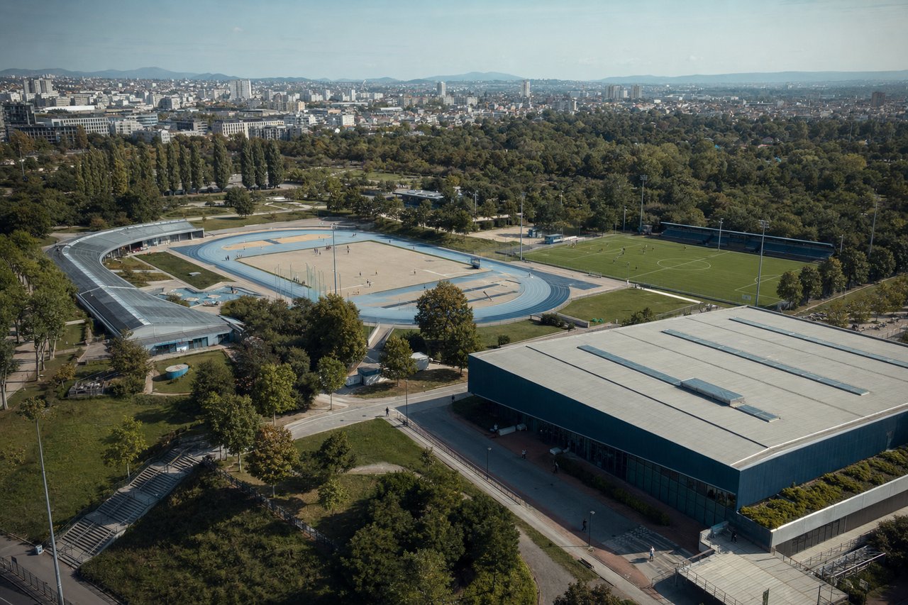 Widok z góry na miejski park sportowy z bieżnią, boiskiem, halą i pływalnią